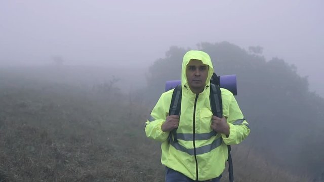 Portrait man tourist with backpack walking alone in the fog,slow mo
