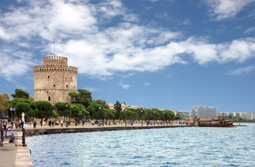 White tower of thessaloniki with a touristic boat on the right - obrazy, fototapety, plakaty