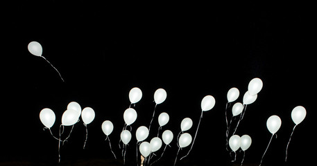Fototapeta premium White Balloons and hand isolated on black background