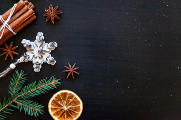 Christmas New Year Composition winter objects fir branch, baubles, cinnamon, ball on dark black background. Flat lay, top view, copy space. Christmas december time for celebration concept