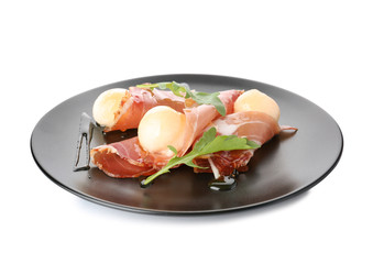 Plate with melon balls and prosciutto on white background