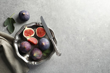 Dish with fresh ripe figs on gray background, top view. Space for text