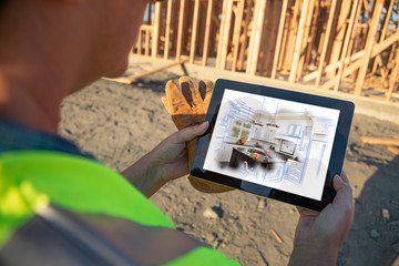 Female Construction Worker Reviewing Kitchen Illustration on Computer Pad at Construction Site