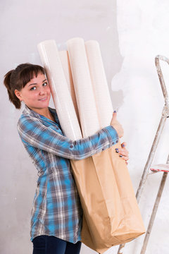 Pretty woman with wallpapers going to repair house