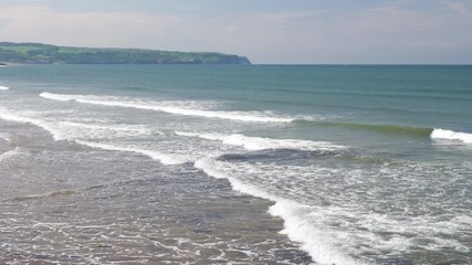 Gentle waves lapping the shore of the beach in Whitby, North Yorkshire.