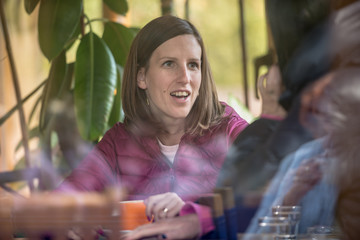 Young woman talking to a friend sitting in a coffee house