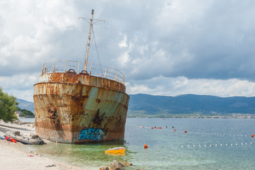 Fototapeta na wymiar Shipwreck on a beach. Tourists swimming. Adriatic Sea.