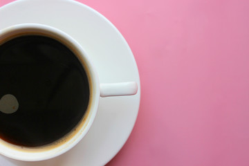 Classic American coffee in a small white ceramic Cup on a pink bright background. The view from the top. Copy space, space for writing texts.