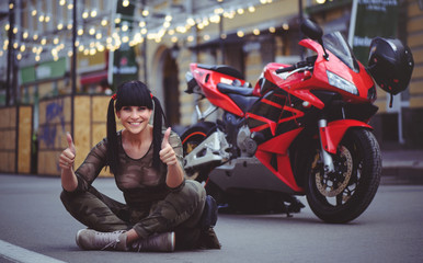 Fototapeta na wymiar happy woman biker sitting near motorcycle and happy, close-up brunette with red bike
