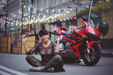Fototapeta na wymiar happy woman biker sitting near motorcycle and happy, close-up brunette with red bike