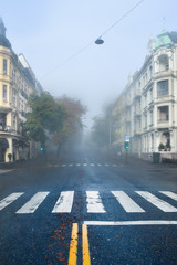Fototapeta na wymiar A magical, beautiful morning. Antique, old buildings. The road goes into the fog. Quiet city foggy morning. Autumn cold morning in a city street. Cloudy day. Oslo, Norway