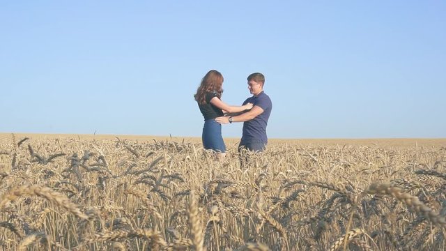 young loving couple in nature in summer on a background of field with oats, there is noise on the video