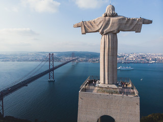 View of The Sanctuary of Christ the King, Cristo Rei, Almada, Lisbon, with 25 de Abril Bridge suspension Bridge, Tagus river, aerial drone view in summer sunny day © tsuguliev