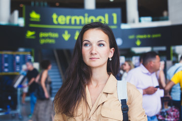 European brunette young girl standing in the airport terminal hall waiting for boarding
