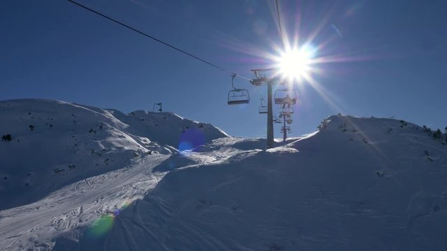 FPV of skier riding on a chairlift on sunny winter day