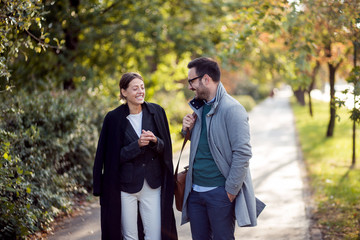 Businessman and businesswoman walking in a park and discussing