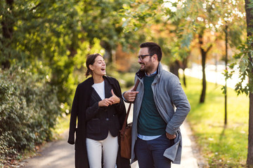 Businessman and businesswoman walking in a park and discussing