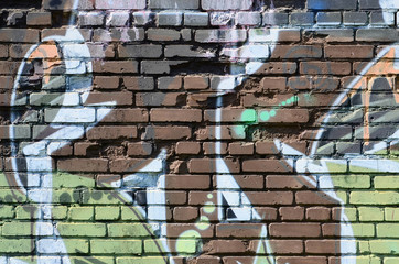 Fragment of graffiti drawings. The old wall decorated with paint stains in the style of street art culture. Colored background texture in warm tones