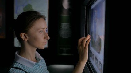 Woman using interactive touchscreen display and looking at 3d models of russian christian orthodox churches