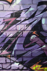 Fragment of graffiti drawings. The old wall decorated with paint stains in the style of street art culture. Colored background texture in purple tones