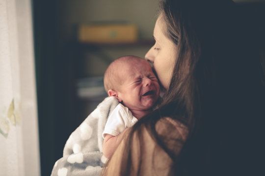 Sweet crying newborn baby at mom on hand lifestyle