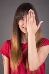 A young girl in a red T-shirt covered her face with her hands