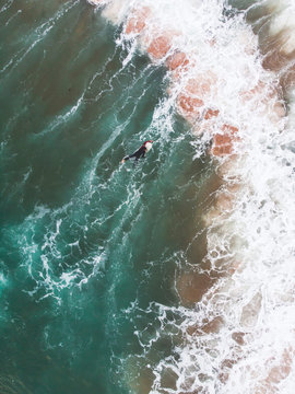 View of Praia do Guincho, Guincho beach, a popular Atlantic Ocean beach on Portugal's Estoril coast, municipality of Cascais, with surfers surfing on the waves, shot from drone