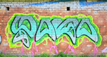 Fragment of graffiti drawings. The old wall decorated with paint stains in the style of street art culture. Colored background texture in green tones