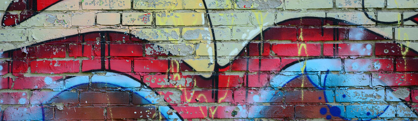 Fragment of graffiti drawings. The old wall decorated with paint stains in the style of street art culture. Colored background texture in warm tones © mehaniq41