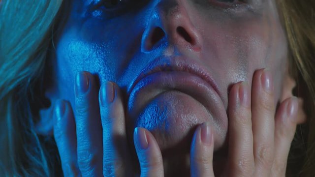 4k, slow motion, Halloween. tired woman in the costume of a terrible witch, erases the make-up from her face with her hands. close-up