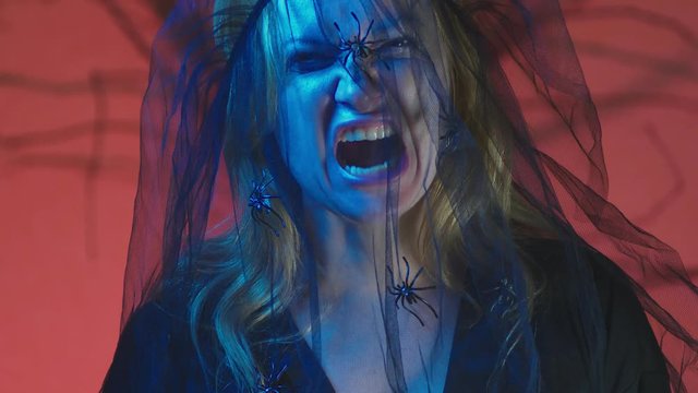 4k, slow motion, Halloween. Woman in costume of a terrible witch, swears looking at the camera, close-up