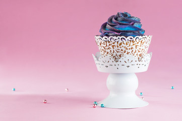 Galaxy cupcake on pink background with copyspace
