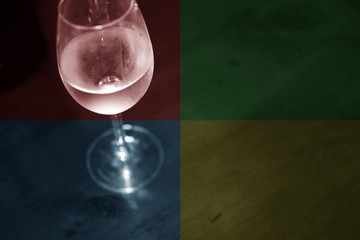 Dark image of white wine in a glass on a dark wooden bench