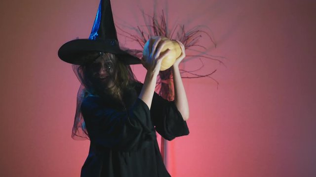 4k, slow motion, Halloween. A woman in the suit of a terrible witch dances with a pumpkin in her hands. space for copying
