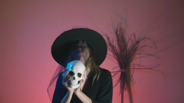 4k, slow-motion, halloween. A woman in the costume of a terrible witch dances with a skull in her hands. copy space
