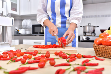 Woman cutting tomatoes with a knife. Process cooking salad Beautiful woman in the kitchen leading healthy life style