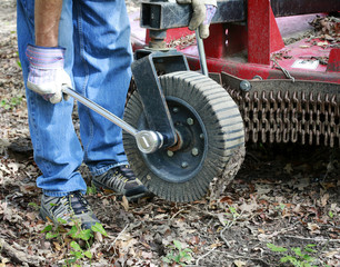 Mechanic repairs dirty and rusty brush cutter, tractor attachment