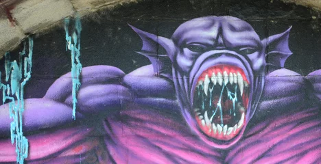 Fragment von Graffiti-Zeichnungen. Die alte Mauer ist mit Farbflecken im Stil der Straßenkunstkultur dekoriert. Lila gruseliges Monster © mehaniq41