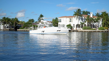 Large motor boat sailing through inner coastal waterway river during summer day time heading towards ocean for water activity. Expensive luxury in tropical destination