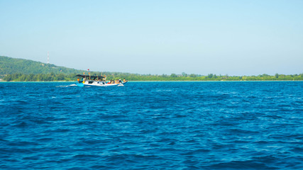 a traditional boat moving fast with green island as background in distance
