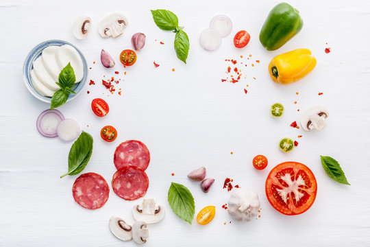 The ingredients for homemade pizza on white wooden background..