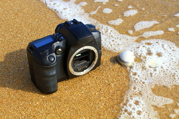 The broken DSLR camera on a wave at the beach. Abstract background. 