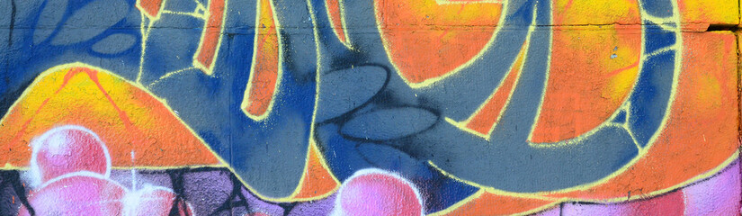 Fragment of graffiti drawings. The old wall decorated with paint stains in the style of street art culture. Colored background texture in warm tones