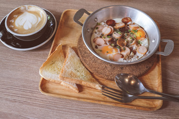 Breakfast fried eggs with sausage and toast in a small pan.