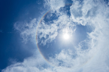 Sun halo with blue sky background with white clouds.