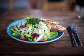 Fresh caesar salad in the plate on dark wooden table.