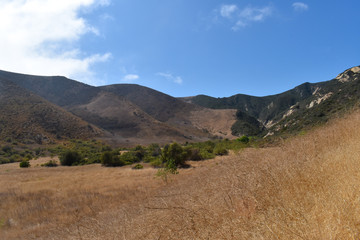 Mountains with clouds casting shadows and a blue sky on a sunny day