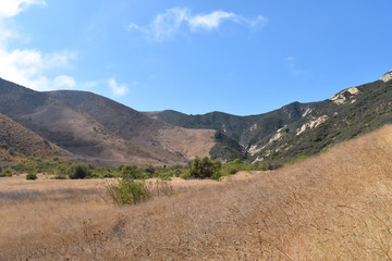 Mountains with clouds casting shadows and a blue sky on a sunny day