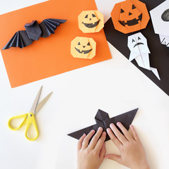  Paper toys of origami for Halloween. Hands of kids.  Preparation for a holiday.