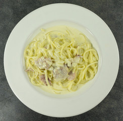 Spaghetti Carbonara in a white plate with Bacon and milk line yellow on a stone floor table,Top view, Copy space Close up..